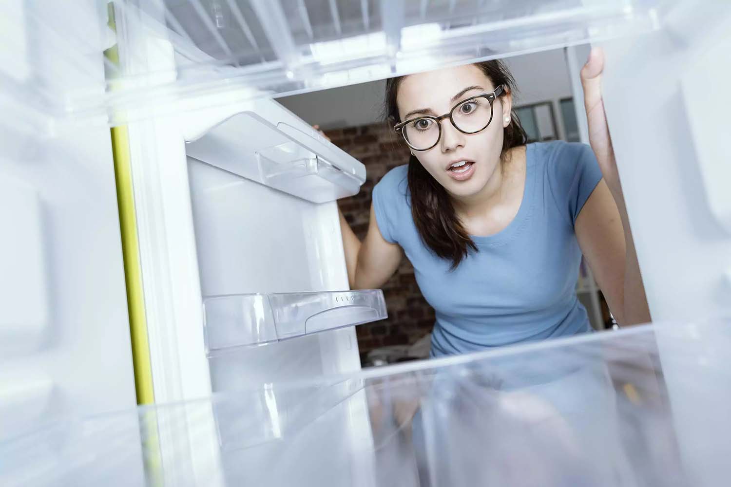 Mujer viendo el refrigerador vacío