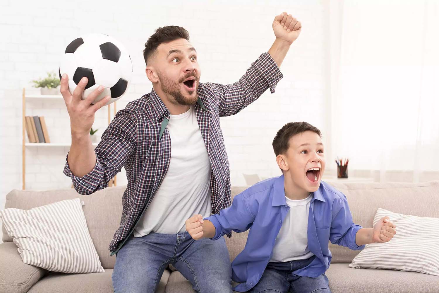 Padre emocionado mira fútbol con su hijo